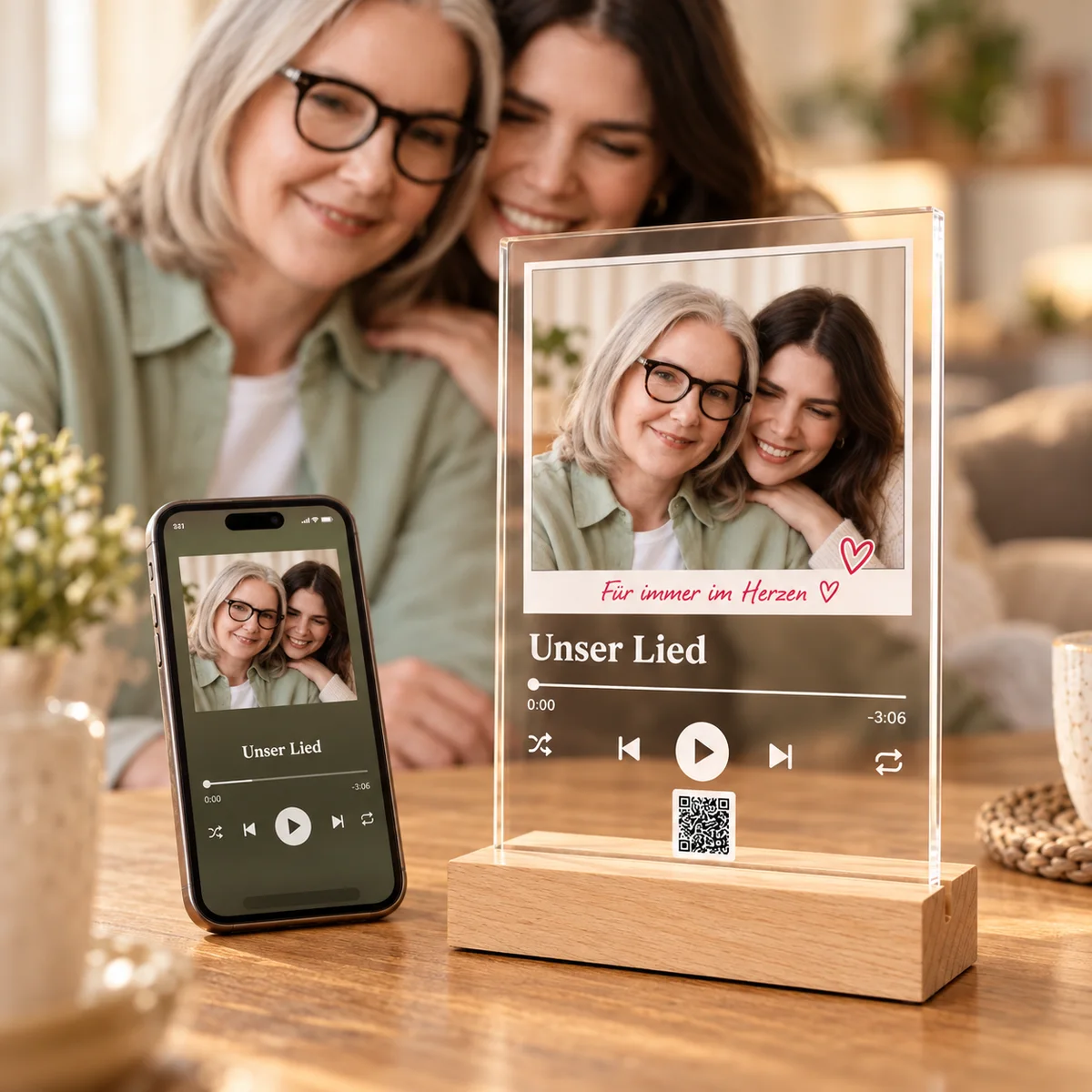 Beispielgestaltung: Mutter und Tochter mit ihrem Foto auf einer Acrylplatte im Holzsockel und ihrem Song auf dem Handy